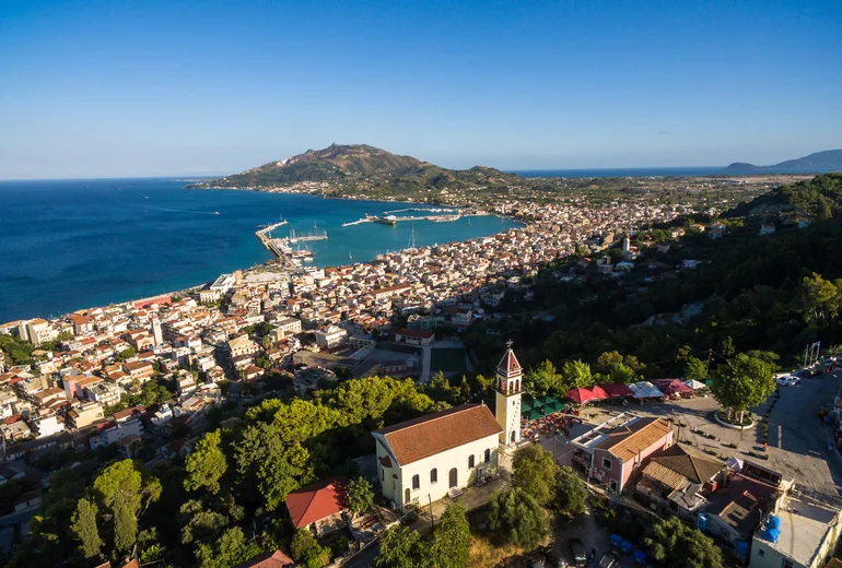 Greek island church on a hill above sailing boats